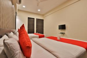 a bedroom with two beds and a television at Hotel Royal Rituals Vesu in Surat