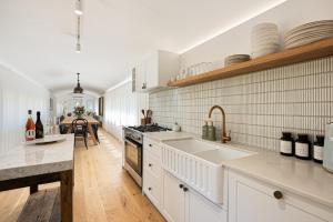 a kitchen with white appliances and a dining room at The Station Hunter Valley in Pokolbin