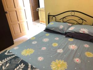 een bed met een blauwe deken met bloemen erop bij Homestay Seri Hampar, Pendang in Pendang