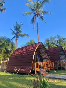a house with a thatched roof and palm trees at Blue Moon Meno in Gili Meno +28 photos