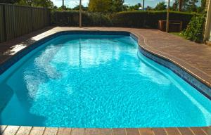 a swimming pool with blue water in a backyard at Fountain View Motel in Dubbo