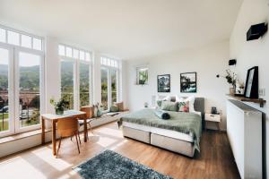 a bedroom with a bed and a table and windows at Mainterrasse Panorama Apartments in Miltenberg