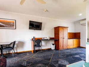 um quarto com uma secretária e uma televisão na parede em Hotel Renmark em Renmark