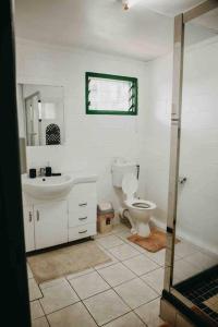 a white bathroom with a toilet and a sink at Heavenly Home in Apia