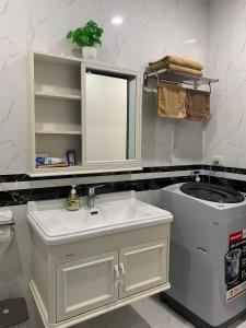 a white bathroom with a sink and a mirror at DK APARTMENT in Hai Phong