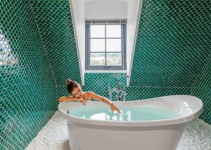 a girl in a bath tub in a green tiled bathroom at Grand Fleuve Boutique in Ha Long