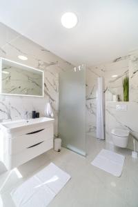 a white bathroom with a sink and a toilet at Villa Renesansa in Milna