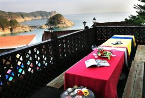 a table on a balcony with a view of the ocean at Solemio Pension in Geoje