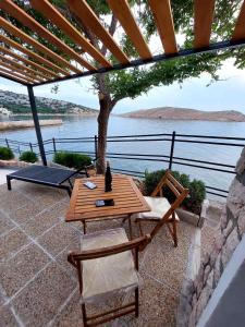 a wooden table and chairs on a patio with a view of the water at Apartman Ulrich in Lukovo