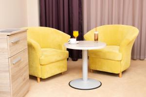 two yellow chairs and a table with a cup and a glass at Casino Motel Senator in Gevgelija