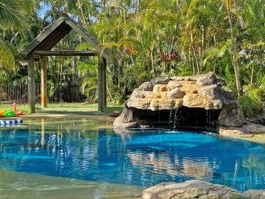 a swimming pool with a waterfall and a rock at BELLES ON BALLOW - POSSUM LODGE in Amity Point