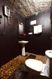 a bathroom with a white toilet and a sink at Private Organic House in Udawalawe