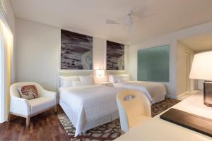 a hotel room with two beds and a desk and a chair at The Westin Langkawi Resort & Spa in Kuah