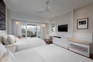 a white hotel room with two beds and a television at The Westin Langkawi Resort & Spa in Kuah