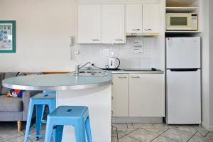 a kitchen with white cabinets and blue stools at Mooloolaba 2 B/R Getaway - Perfect location ZD5 in Mooloolaba