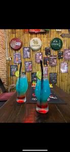 two cocktails on a wooden table with signs on the wall at Sue@Cozy Guesthouse in Kata Beach