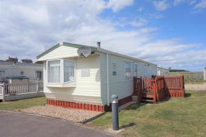 a small white house sitting in a yard at Great 6 Berth Caravan With Decking By The Beach In Suffolk Ref 40023nd in Lowestoft
