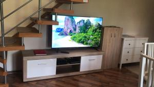 a flat screen tv sitting on a wooden entertainment center at Lagom Apartman in Gyula