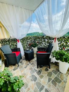 a patio with chairs and potted plants and curtains at Aici te simți ca acasa in Iaşi