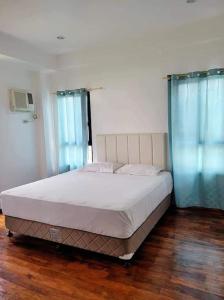 a bed in a bedroom with blue curtains and a wooden floor at Lux 7 Pool Villa Mactan in Mactan