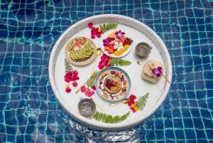 a plate of food on a table next to a swimming pool at Soul Villas by The Beach - Phuket in Panwa Beach