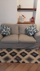 un sofá con 2 almohadas y una alfombra en la sala de estar en Casa Adua, en Donoratico