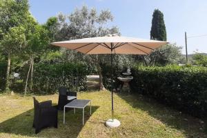 a tan umbrella and two chairs and a table and chairs at Casa Adua in Donoratico