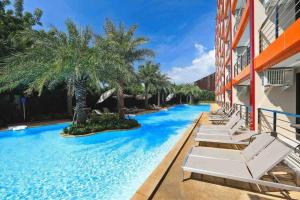 a resort swimming pool with lounge chairs and palm trees at NEW one bedroom apartment MBC E in Ban Bo Sai Klang
