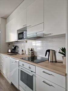 a white kitchen with white cabinets and a tea kettle at Huhta Sport in Jyväskylä
