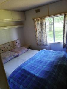1 dormitorio con 1 cama con edredón azul y ventana en Kempings Mežmalas en Usma