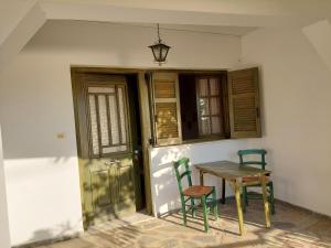 une table et deux chaises assises à côté d'une porte dans l'établissement PORTO KATSIKI-HOME, à Athani