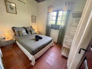 een slaapkamer met een bed en een raam bij Bungalow Gaspardo , 2 chambres climatisées , à 2 mins à pied de la plage , wifi , jardin clos, parking ,sans vis-à-vis au Carbet in Le Carbet