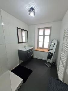 uma casa de banho branca com um lavatório e um espelho em l'annexe des Remparts em Rocroi