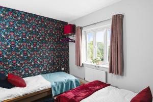 a bedroom with two beds and a floral wallpaper at TravelNest Property in Bristol