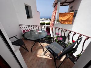 a balcony with a glass table and chairs on it at Casa Dora in Anacapri