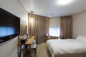 a hotel room with a bed and a flat screen tv at Elin Hotel in Jeju