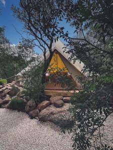a tent with a yellow sign in a pile of rocks at Pasare Glamping_AnglonaRuralExperience in Perfugas