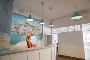 une femme assise au comptoir dans une pièce dans l'établissement Hostal Sunset Ibiza, à Sant Antoni de Portmany