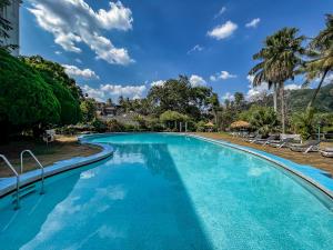 una piscina con agua azul y palmeras en Hotel Suisse, en Kandy