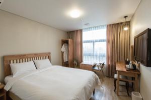 a bedroom with a bed and a desk and a television at Elin Hotel in Jeju