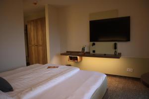 ein Hotelzimmer mit einem Bett und einem Flachbild-TV in der Unterkunft Wohlfühlhotel DER JÄGERHOF in Willebadessen