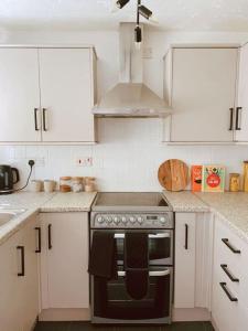 a kitchen with white cabinets and a stove top oven at Cosy & stylish home from home in Peterborough