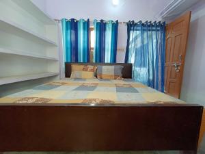 a bed in a bedroom with blue curtains at OYO Home Anjaneya Guest House Homestay in Ayodhya