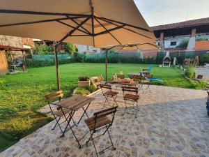 a patio with tables and chairs and an umbrella at La Bolgora Guesthouse in Recetto