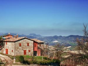 una vieja casa de piedra en una colina con montañas en el fondo en Flat on a farm with swimming pool and many activities, en SantʼAngelo in Vado