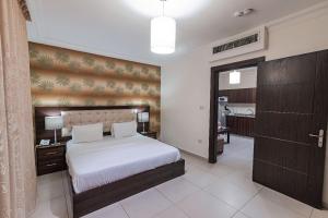a bedroom with a large white bed and a hallway at Lancaster Hotel Apartments-Gardens in Amman
