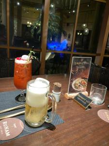 a table with two glasses of beer and a book at Leto Hotel Central Sunset Town in Phú Quốc