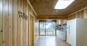 a kitchen with wooden walls and a white refrigerator at Solemio Pension in Geoje