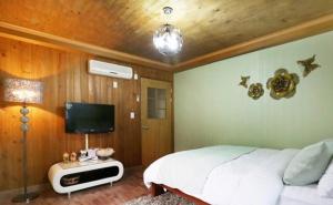 a bedroom with a bed and a flat screen tv at Solemio Pension in Geoje