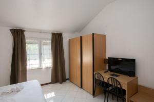 1 dormitorio con 1 cama y escritorio con TV en Hotel Villa Elia, en Calizzano
